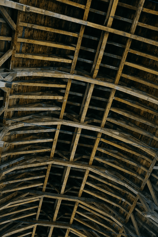 Alte Holzbalkendecke eines langgestreckten Daches, von unten gesehen