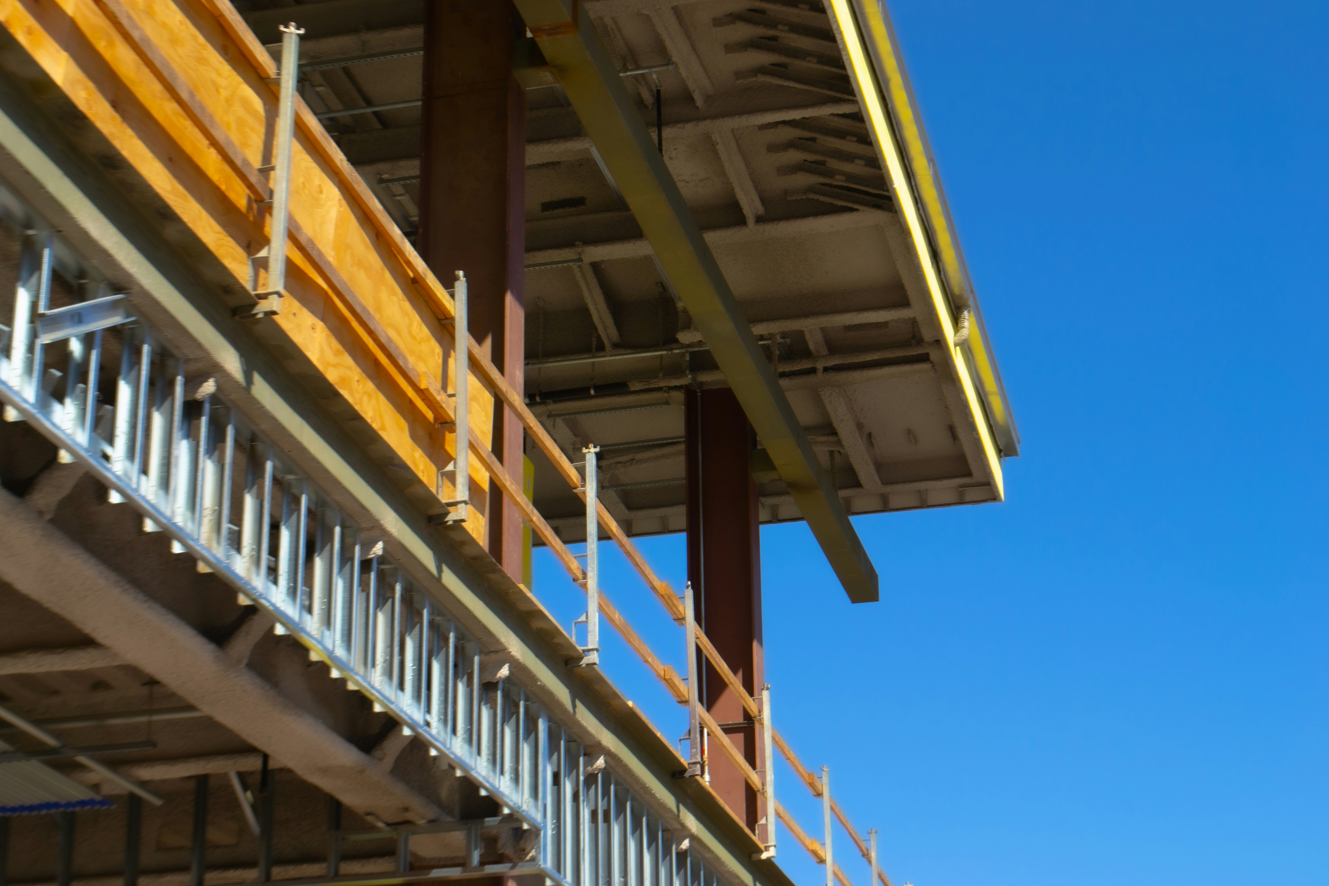 Gebäude in der Bauphase, mit Stahlträgern, offener Dachkonstruktion, daneben blauer Himmel